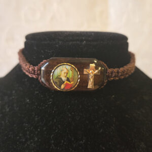 ulsera de Hilo en color café, tamaño ajustable con un centro de Imagen de  San Benito,  impresa a colores  y la imagen de una cruz al lado. Centro de la Pulsera de madera con imagen mide 1 Pulgada de ancho ½ Pulgada de alto . Brown thread bracelet, adjustable in size, with a center image of  St Benedict, printed in color and a cross on the side. The wooden bracelet center with the image measures 1 inch wide and 1/2 inch tall.