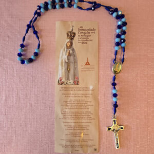 Rosario de cristal en tonos azul rey y azul cielo crucifijo de San Benito, centro de la virgen de Fatima impreso a colores, y al reverso imagen de los sagrados corazones, hecho de hilo en tono de color azul rey hecho a mano. Viene acompañado de una oración jubilar de consagración a nuestra señora de Fátima Medidas del rosario, cuenta de cristal mide 8 mm, Crucifijo mide 1 pulgada de ancho y 2 pulgadas de alto, Longitud del rosario 18 Pulgadas (desde el final de la cruz hasta la mitad de la Tercera década), el tamaño del centro del rosario es de ½ pulgada. 1.3 Oz.