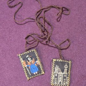 Escapulario de tela color café  bordado  En la parte delantera muestra imagen santo niño de Atocha   cuerpo completo,  en la parte de atrás muestra imagen de su parroquia, cordón delgado. Medidas de la insignia escapular 1 pulgadas ancho  de la insignia escapular, 1.15 pulgadas alto Longitud del cable escapular: panel a panel 17 pulgadas Peso .3 Oz Medida sobre 4*9 ½ Alto 1 pulgada 